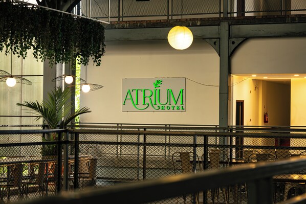 Hotelinterieur met een bordje voor 'Atrium Hotel', zitgedeeltes en hangplanten.
