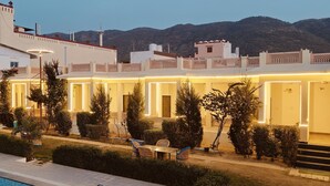 Un hotel con varios balcones, piscina y montañas al fondo.