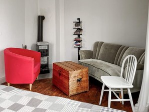 A living room with a red armchair, a grey sofa, a white chair, a wooden chest, and a black bookshelf against the wall. - 4 Star Holiday Home in Vaddo (Väddö)