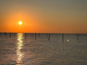 A sunset over a calm body of water with wooden posts in the foreground.