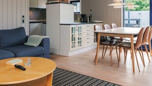 A modern kitchen with a clock, a dining area with a table and chairs, a sofa, and a coffee table.