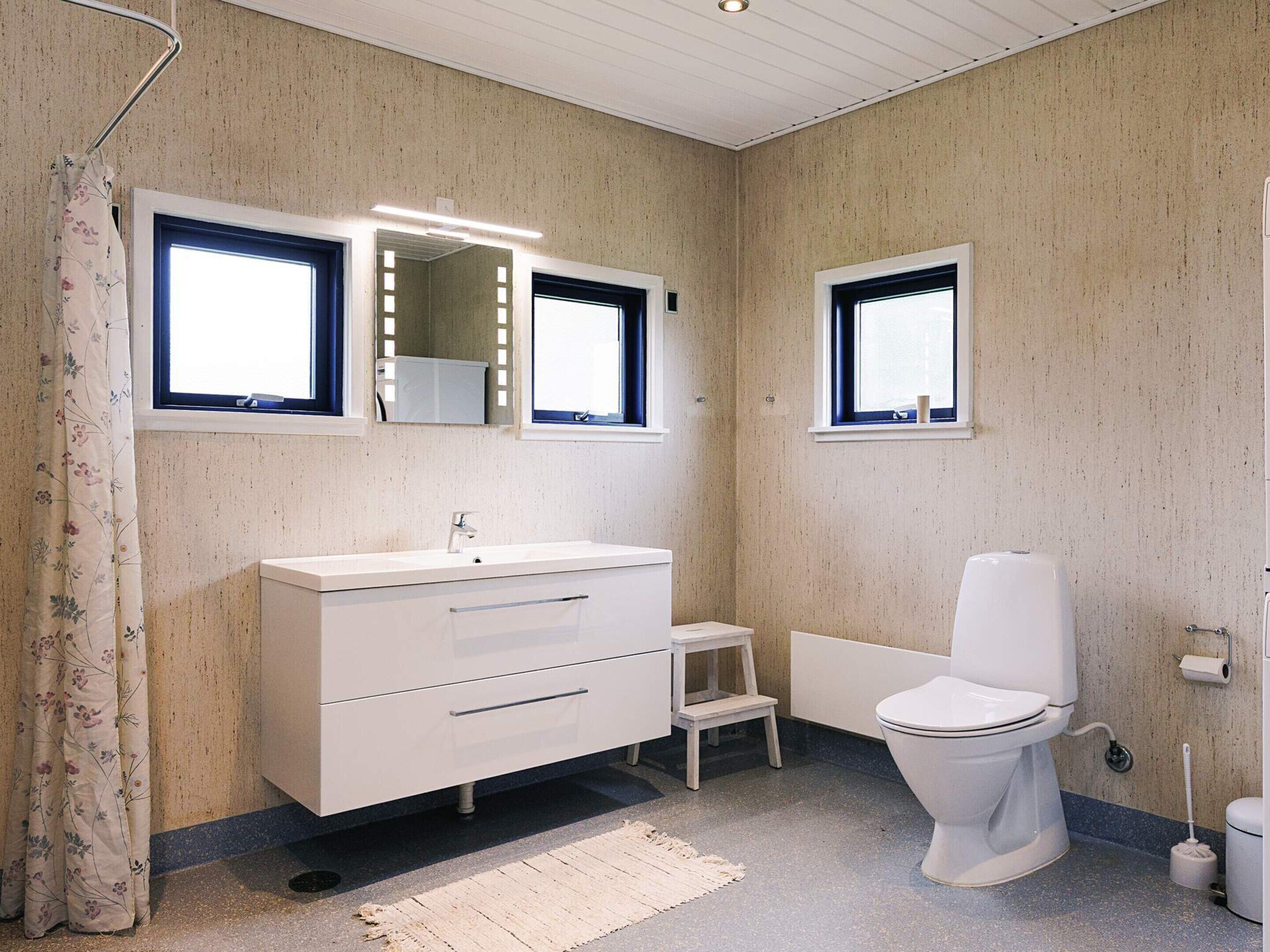 A bathroom with a white vanity, a toilet, and a small step stool.