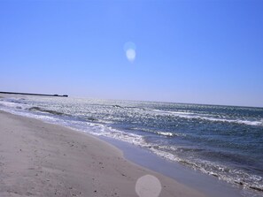 A beach with a clear sky, calm sea, and a distant pier. - 8 Person Holiday Home in Nakskov (Nakskov)
