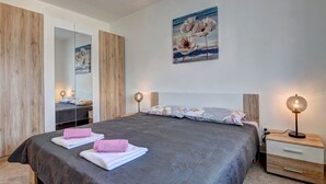 Un dormitorio con cama, mesitas de noche, un espejo y un cuadro en la pared.