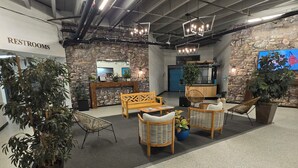 A lobby with a stone wall, wooden furniture, and potted plants.
