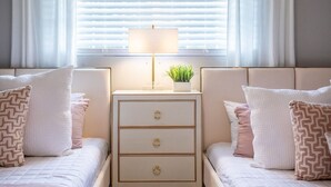 Une chambre avec deux lits, une table de chevet avec une lampe et une fenêtre avec des stores.