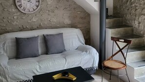 Un salon comprenant un canapé, une table basse, un fauteuil, une horloge et un escalier.