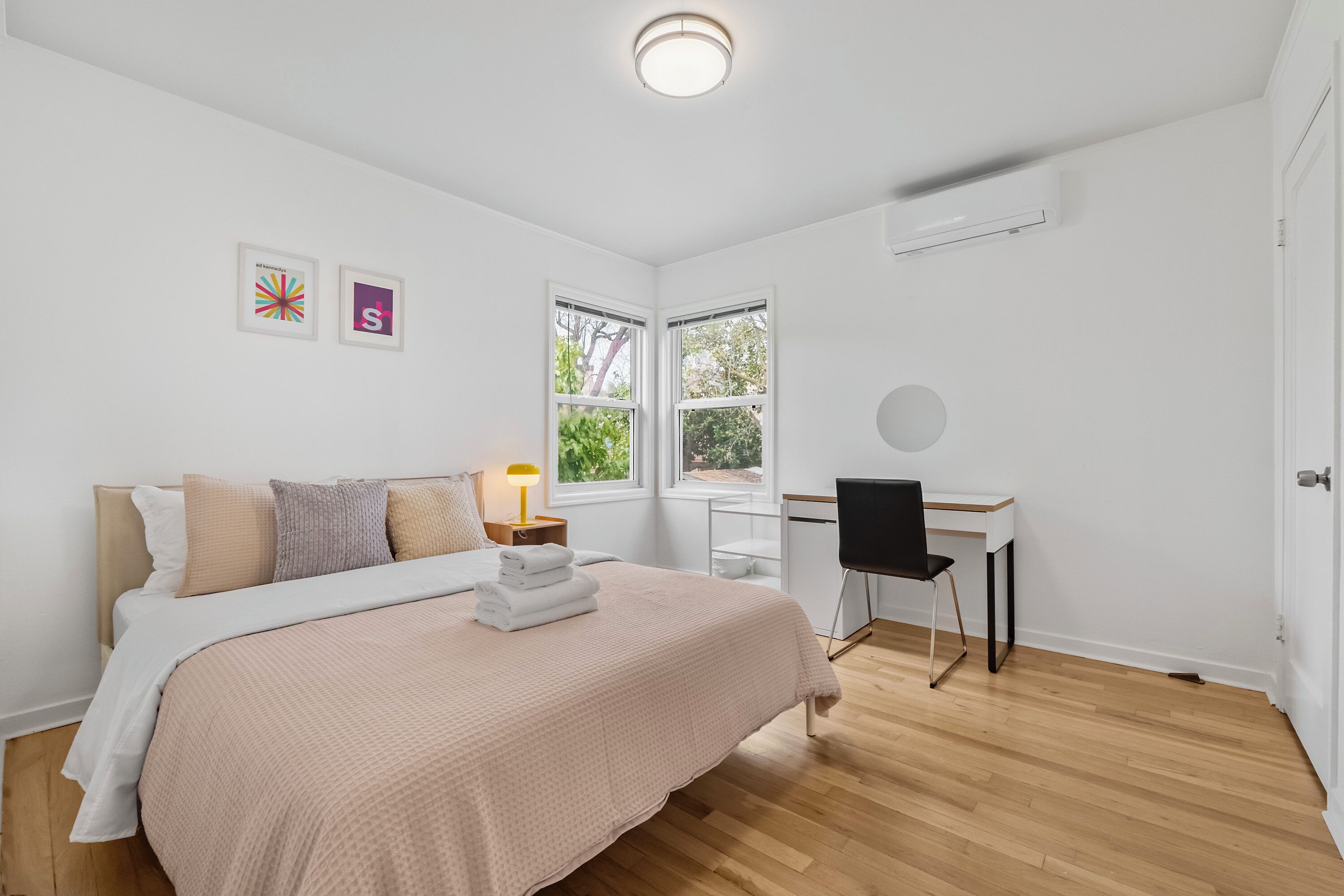 A modern bedroom with a bed, bedside table, lamp, desk, and chair.