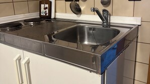 Una cocina con un lavamanos de acero inoxidable, armarios blancos y un salpicadero de azulejos.