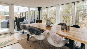 Un comedor moderno con una mesa de madera, sillas blancas y una silla colgante negra.