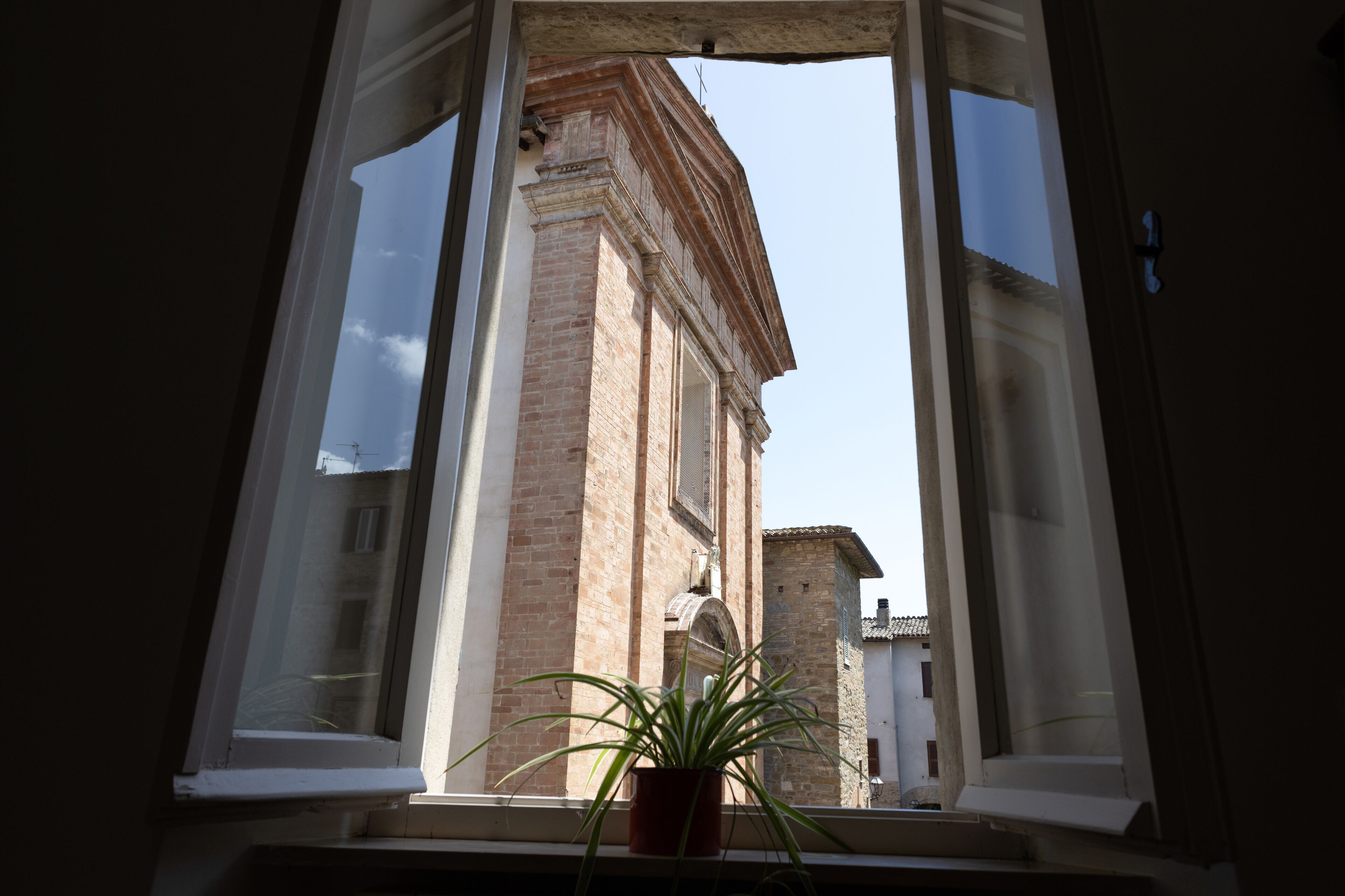 A window with a view of a building with arched windows and a brick facade.