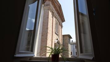 A window with a view of a building with arched windows and a brick facade.