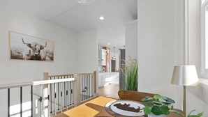 Un interior moderno con una escalera, un comedor con mesa y sillas, una cocina al fondo e impresión enmarcada de un animal en la pared.