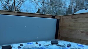 Un jacuzzi con chorros, un panel de control y una terraza de madera alrededor.