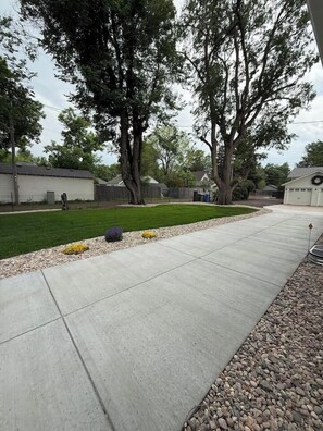 A residential driveway with a concrete path, a well-maintained lawn, and a garage.