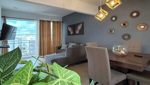 Een moderne woonkamer met een bank, eettafel, stoelen en decoratieve wandkunst.