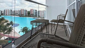 Een balkon met rieten meubilair met uitzicht op een zwembad en een stadsbeeld.