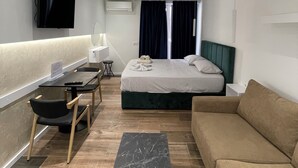 A modern hotel room with a bed, a sofa, a dining table, and a TV. - Superb 1-bedroom apartment in Tiranë (Tiranë)