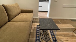 A living room with a beige sofa, a dark marble coffee table, and a patterned rug. - Superb 1-bedroom apartment in Tiranë (Tiranë)