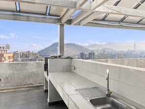Une terrasse sur le toit offrant une vue sur le paysage urbain, avec des montagnes et des bâtiments en toile de fond.