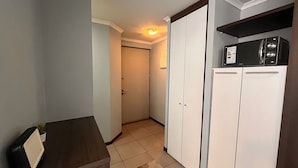 A hallway with a kitchenette area, a door leading to another room, and a small plant on a counter. - Oceana Suites Vista Parque (Santiago)