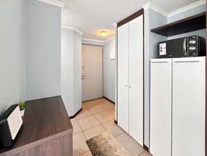Une chambre d’hôtel avec un bureau en bois, un four à micro-ondes et une armoire.
