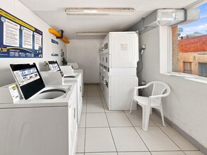 Une buanderie équipée d’une machine à laver et d’un sèche-linge superposés, d’une chaise et d’un tableau d’affichage contenant des conseils pour le lavage du linge.
