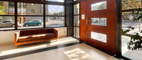 A lobby with a wooden bench, large windows, and a view of the street.