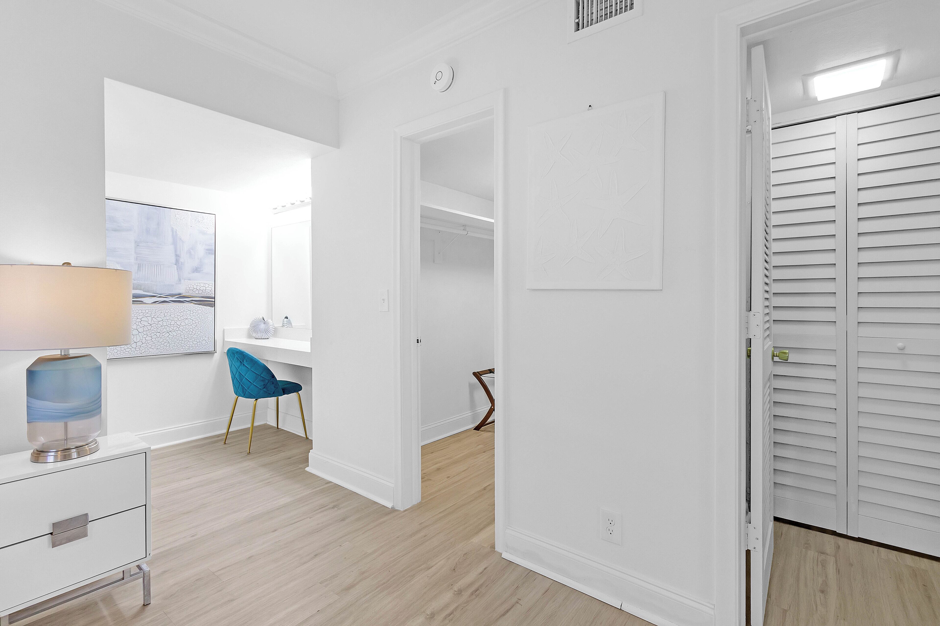 Et moderne, lyst værelse med skrivebord, stol og lukket skab.