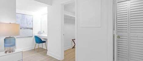 Et moderne, lyst værelse med skrivebord, stol og lukket skab.