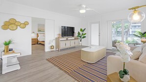 En rummelig stue med moderne design, der inkluderer et stort fladskærms-tv, en behagelig sofa, et sofabord og en dekorativ plantetilpasning.