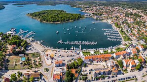 Luftaufnahme einer Küstenstadt mit einem Yachthafen, Wohngebäuden und einer kleinen Insel.