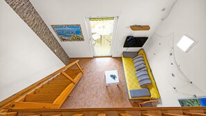 Eine Treppe führt zu einem Raum mit einer Couch, einem kleinen Tisch und einem an der Wand befestigten Fernseher.