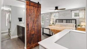 A bedroom with a bed, bedside tables, a ceiling fan, and a sliding barn door.