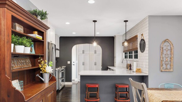 Una cocina moderna con armarios blancos, una barra de madera y una isla central con taburetes.