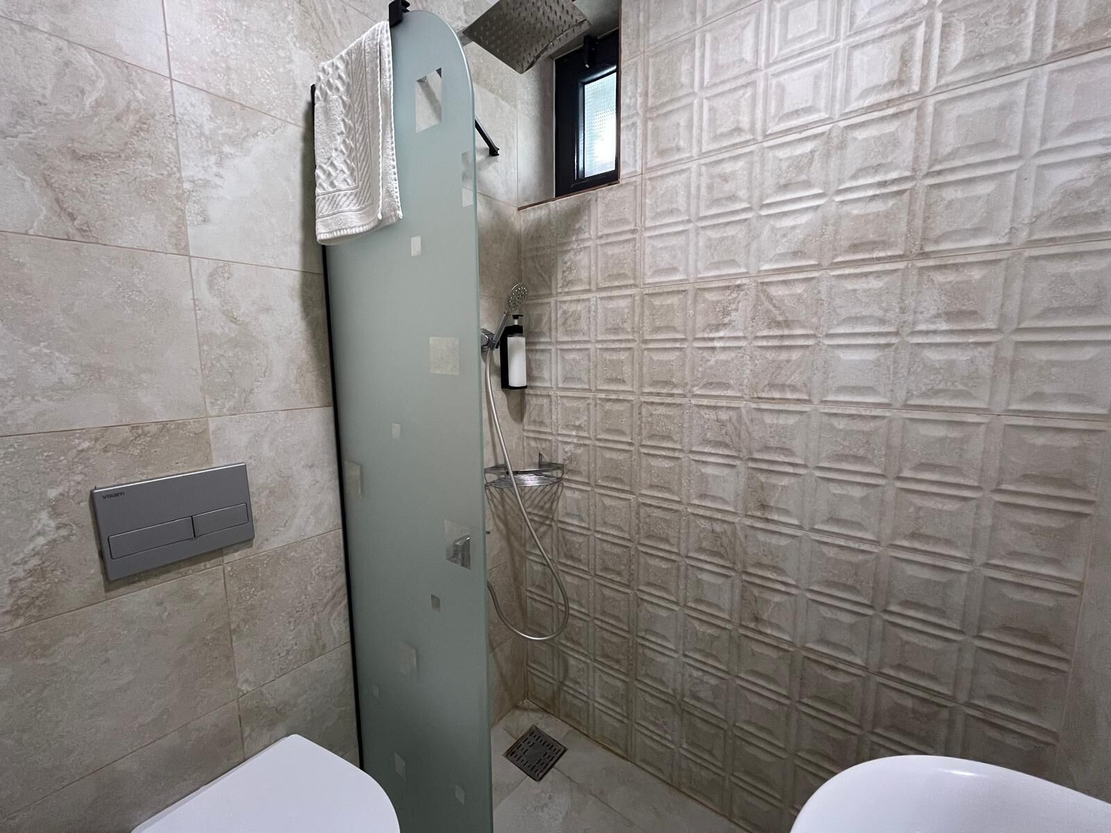 Un baño con ducha, inodoro y toallero.