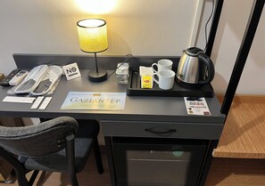 A hotel desk with a lamp, a tray with mugs, a kettle, a sign, and a minibar. - HOTEL GAZİ (Gaziantep)