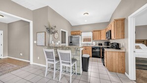 A compact kitchen with a central island, wooden cabinets, and modern appliances. - Pet Friendly Home near Downtown Weatherford! Bring the Family, Relax & Enjoy! (Weatherford)