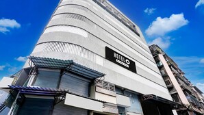 Un hotel con diseño moderno, que destaca un cartel grande que dice 'HOTELO' y una fachada curva.