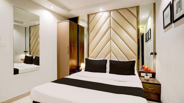 Una habitación de hotel moderna con una cama grande, un armario, una mesita de noche y un espejo.