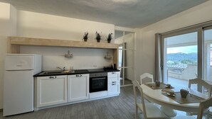 Una cucina moderna con mobili bianchi, forno integrato e zona pranzo con tavolo e sedie.