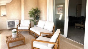 Un balcone luminoso con un divano bianco, un tavolino in legno e una pianta in vaso.