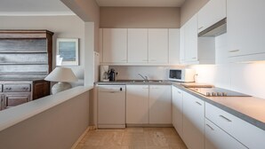 A compact kitchen with white cabinets, a microwave, a coffee maker, and a dishwasher. - Apartment in Knokke-heist by the Seafront (Knokke-Heist)