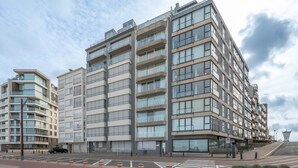 A modern multi-story residential building with balconies, large windows, and a pedestrian walkway in front. - Apartment in Knokke-heist by the Seafront (Knokke-Heist)