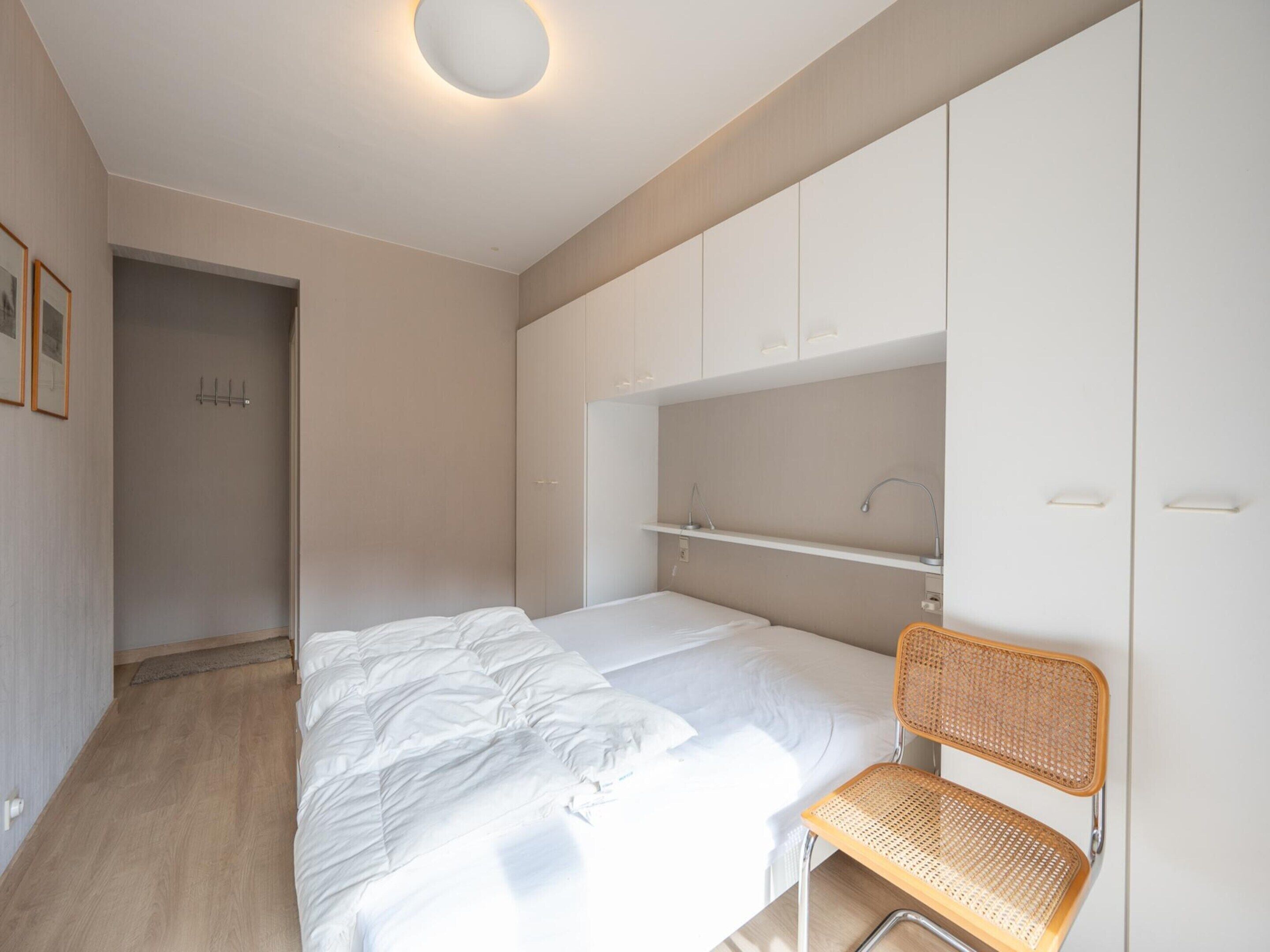 Un dormitorio moderno con una cama, una silla y armarios empotrados.