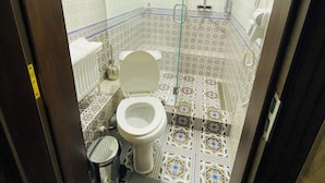 A small, tiled bathroom with a toilet, bidet, and shower.