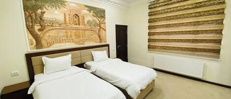Habitación de hotel con dos camas, un gran mural en la pared y una ventana con persiana a rayas.