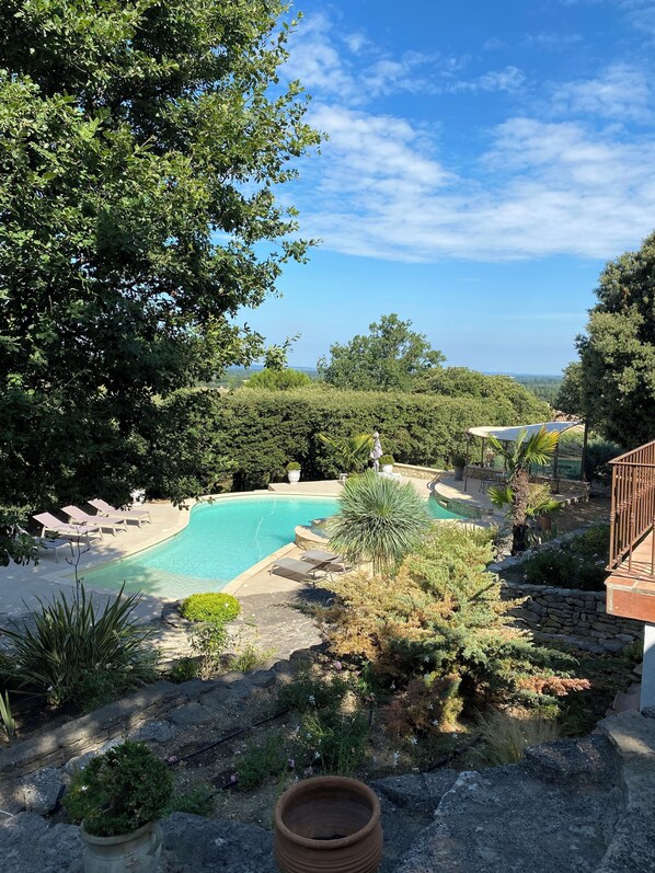 A pool area with lounge chairs, surrounded by lush greenery and a view of the landscape. - La Souvenance, listed villa, panoramic view (Lagnes)