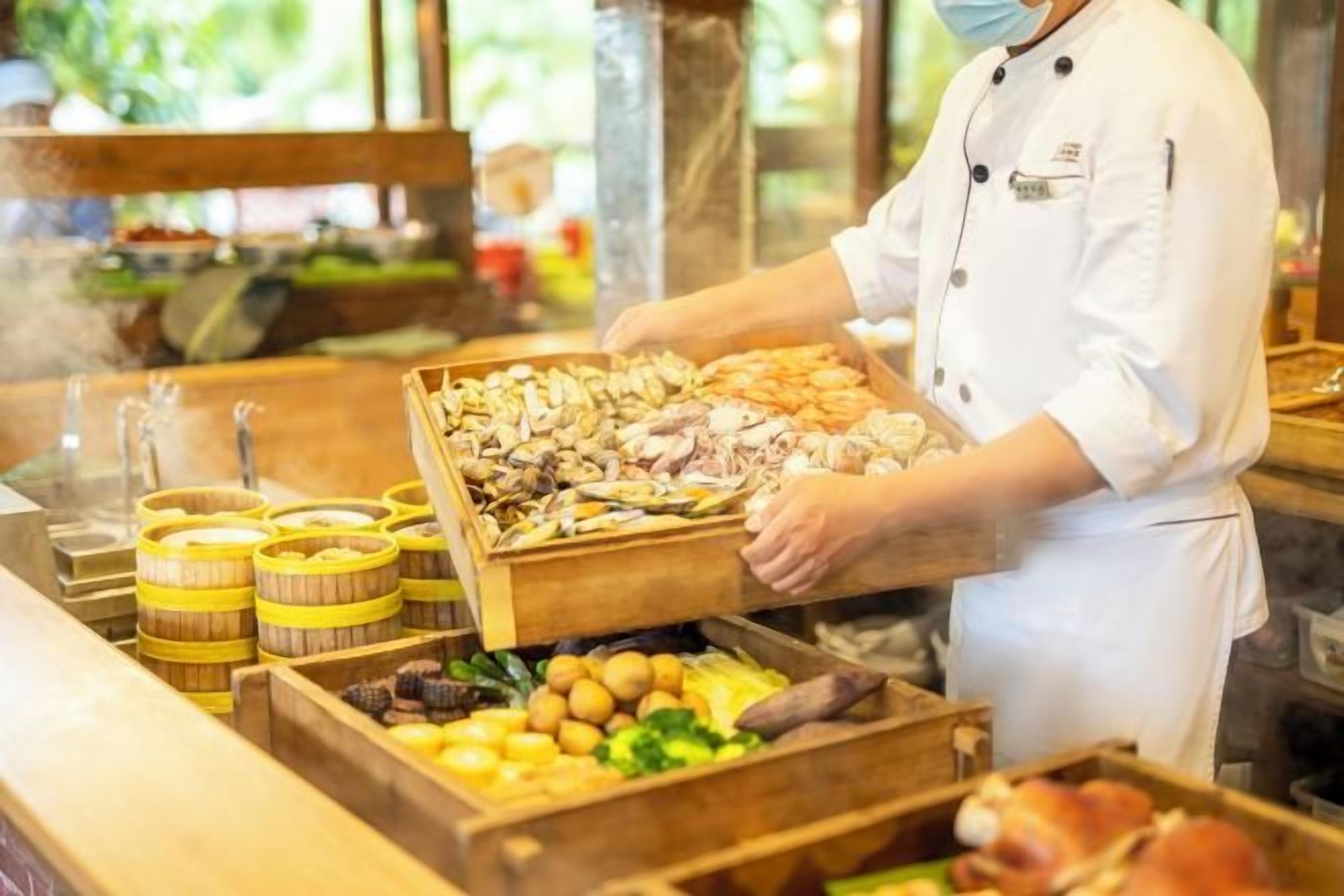 Een buffetopstelling met diverse soorten eten en een persoon die bedient.