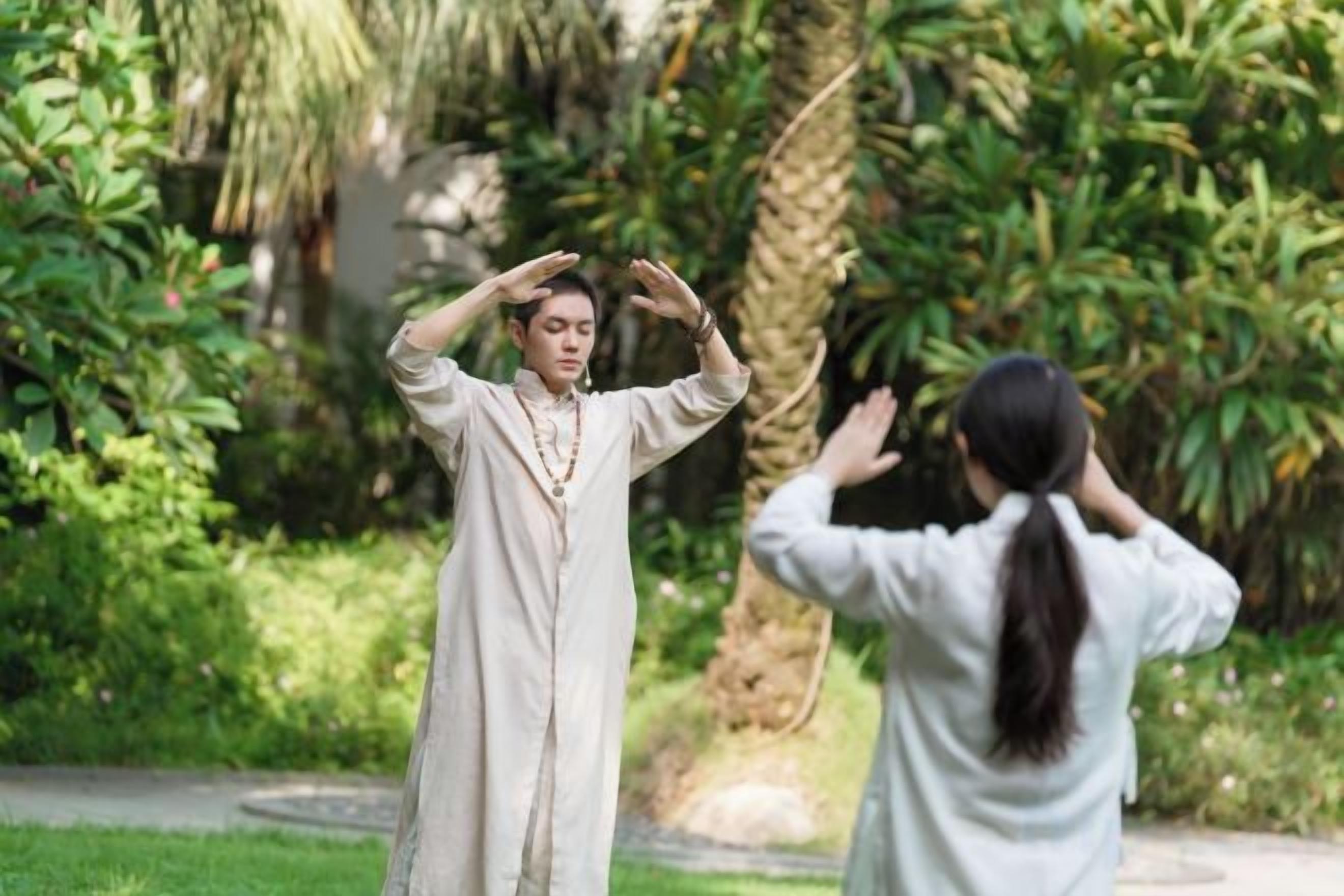 Two individuals practicing a form of meditation or yoga outdoors.